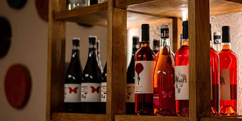 Detall d'unes ampolles de vi rosat en unes estanteries.